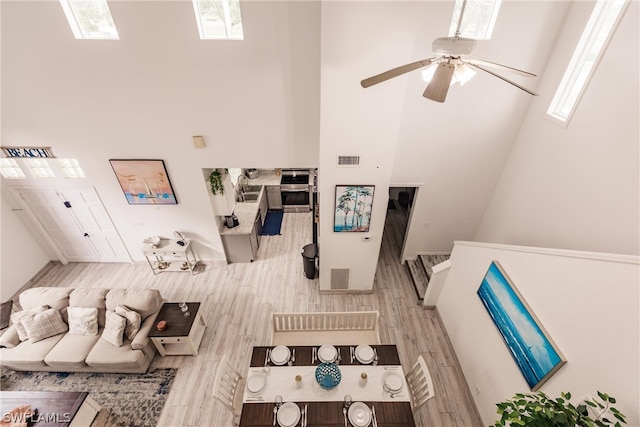 living room with plenty of natural light, ceiling fan, hardwood / wood-style floors, and a high ceiling