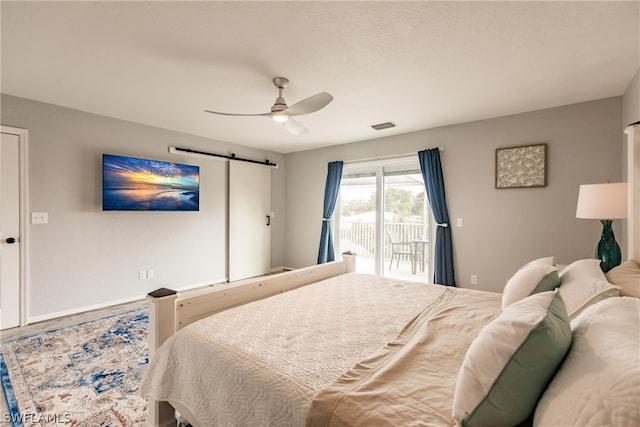 bedroom with ceiling fan, access to exterior, and a barn door