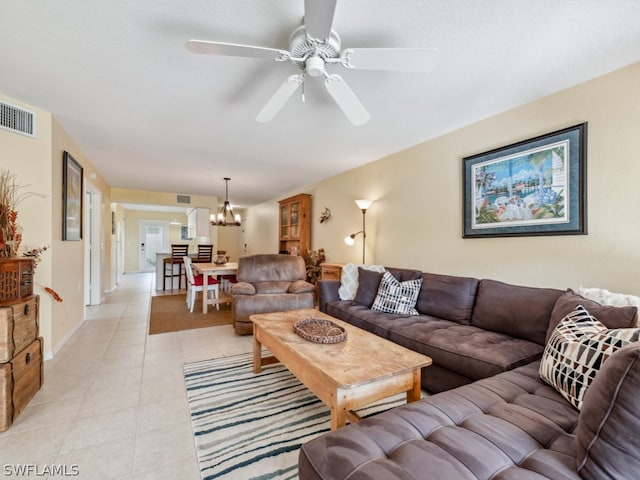 tiled living room with ceiling fan with notable chandelier