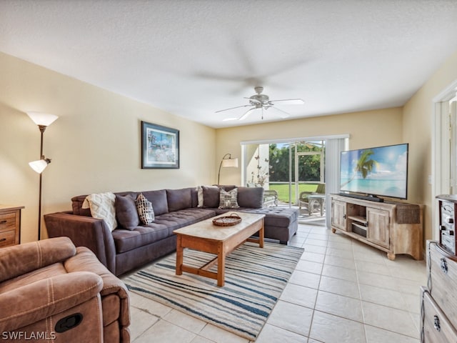 living room featuring ceiling fan, light tile floors, and a textured ceiling