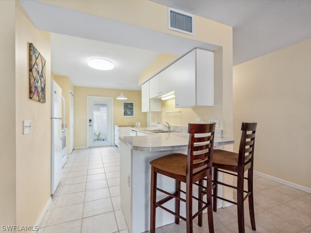 kitchen featuring light tile floors, sink, white cabinets, and a kitchen bar