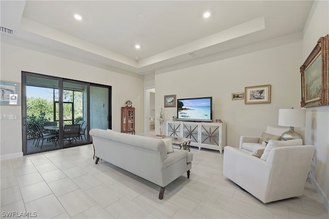 living room featuring a raised ceiling and light tile floors