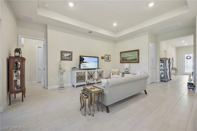 living room featuring light tile floors and a raised ceiling