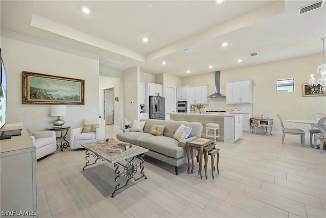 living room featuring a chandelier and a raised ceiling