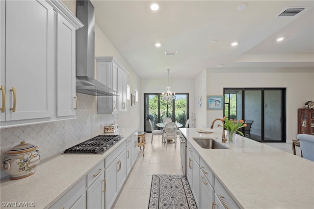 kitchen with wall chimney exhaust hood, light tile flooring, backsplash, stainless steel gas stovetop, and sink