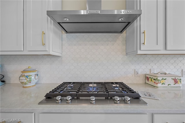 kitchen with wall chimney exhaust hood, tasteful backsplash, white cabinetry, and stainless steel gas stovetop