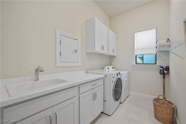 laundry area with light tile floors, washer and clothes dryer, cabinets, and sink