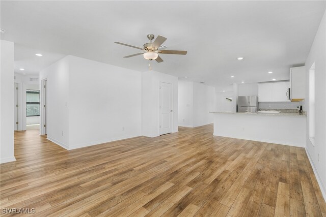 unfurnished living room with ceiling fan and light hardwood / wood-style floors