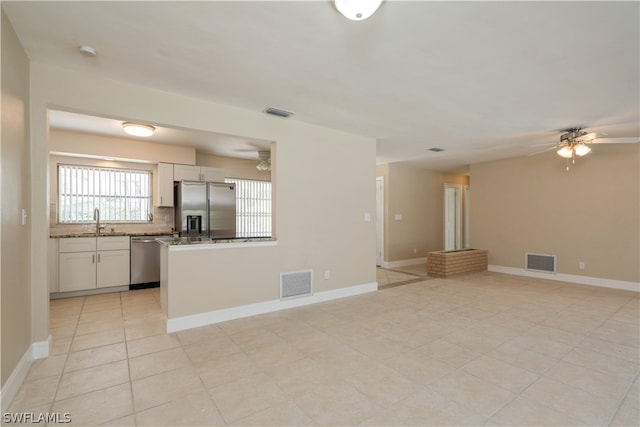 kitchen featuring white cabinetry, stainless steel appliances, light tile floors, tasteful backsplash, and ceiling fan