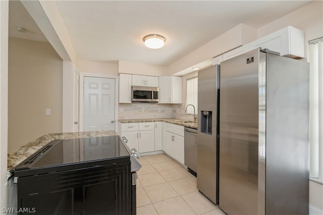 kitchen with light stone counters, appliances with stainless steel finishes, light tile floors, white cabinets, and tasteful backsplash