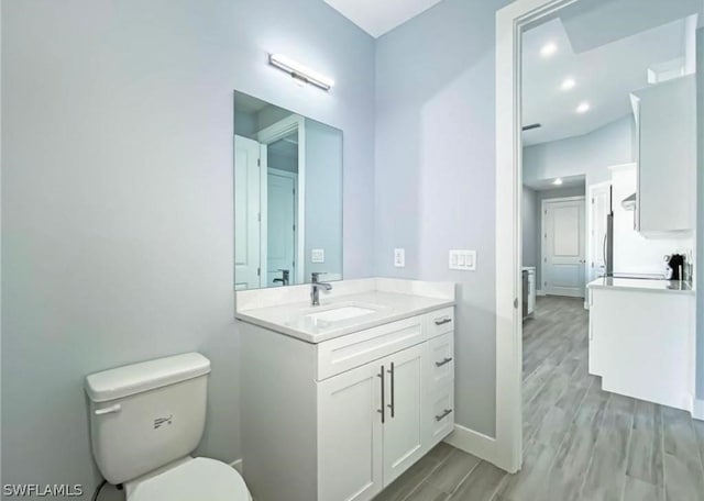 bathroom with oversized vanity, toilet, and hardwood / wood-style flooring