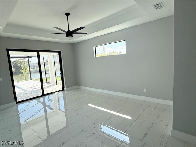 unfurnished room featuring a raised ceiling and ceiling fan