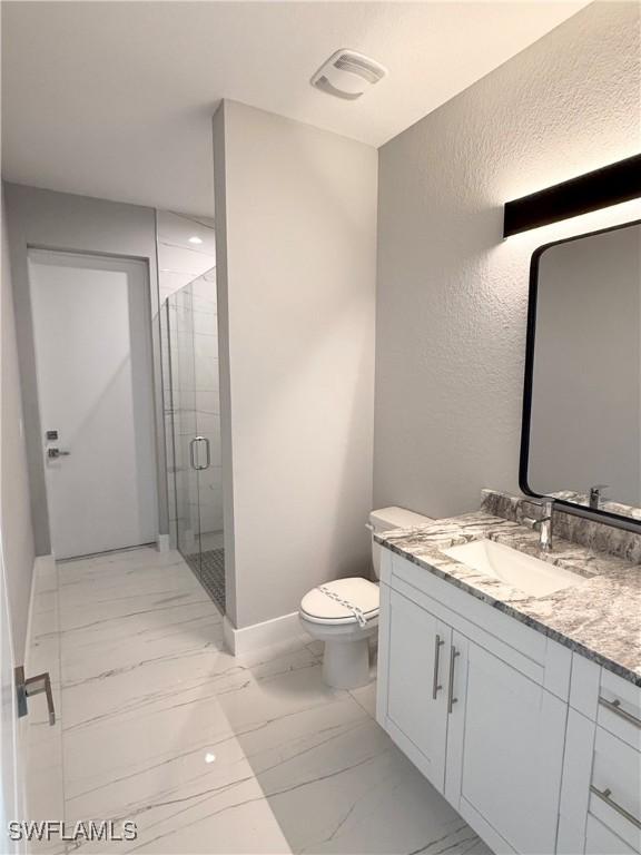 bathroom with toilet, a shower with door, and vanity