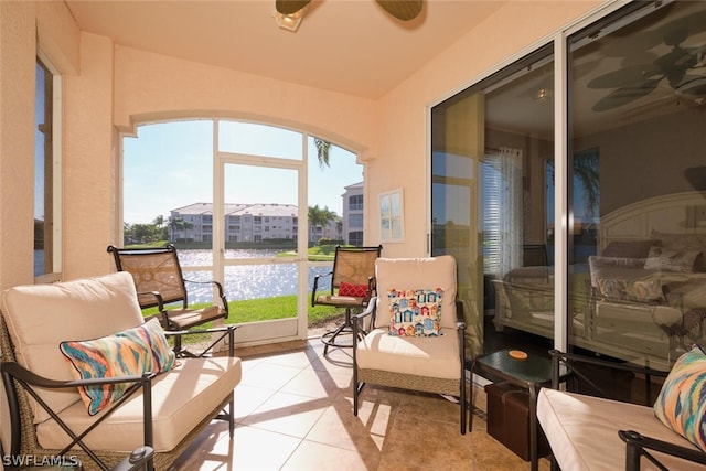 sunroom with ceiling fan and a water view