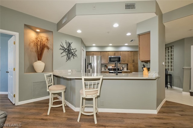 kitchen featuring sink, kitchen peninsula, stainless steel appliances, and a breakfast bar