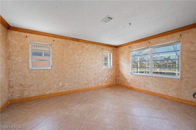 spare room featuring light tile patterned flooring, crown molding, and a textured ceiling