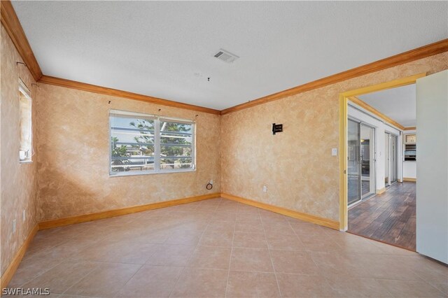 spare room featuring a textured ceiling, light hardwood / wood-style floors, and crown molding