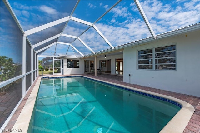 view of swimming pool with glass enclosure, ceiling fan, and a patio