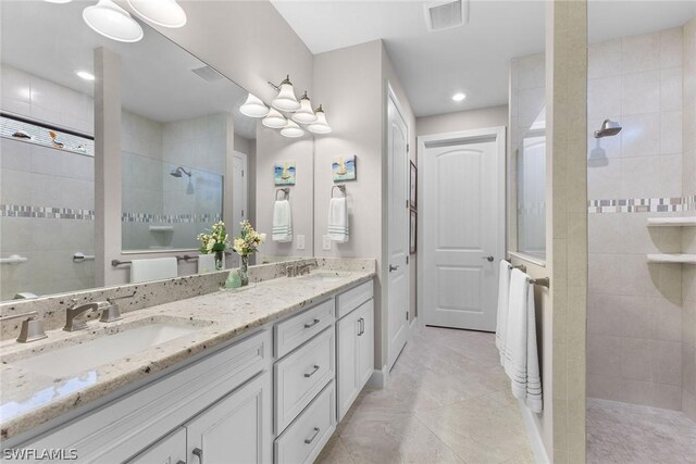 bathroom with tile patterned flooring, vanity, and a tile shower