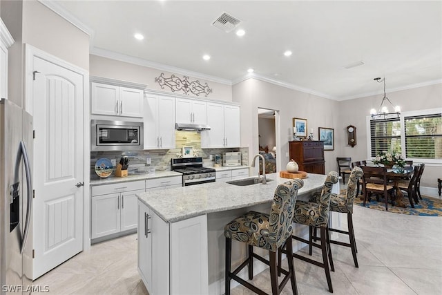 kitchen featuring white cabinetry, sink, decorative light fixtures, a center island with sink, and appliances with stainless steel finishes