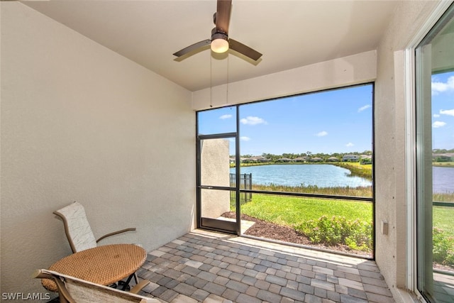 sunroom featuring a water view and ceiling fan