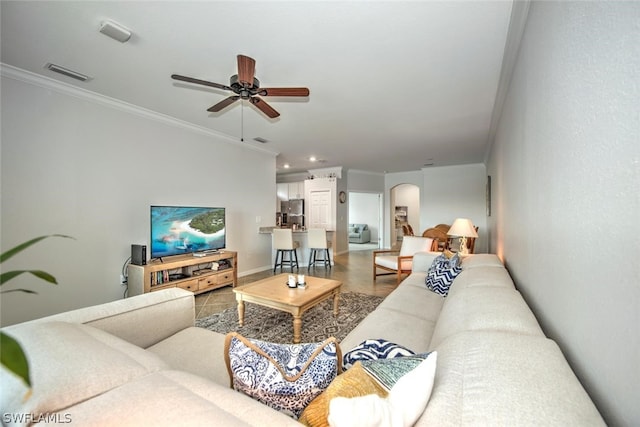 tiled living room featuring ornamental molding and ceiling fan