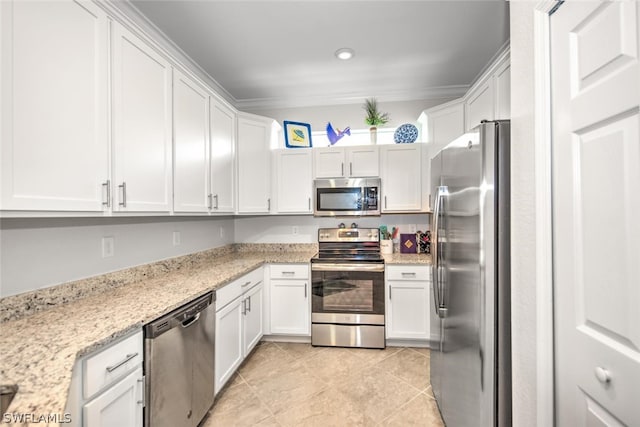 kitchen with white cabinets, light stone countertops, light tile flooring, crown molding, and appliances with stainless steel finishes