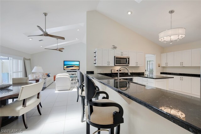 kitchen featuring pendant lighting, white cabinets, light tile flooring, stainless steel appliances, and dark stone countertops