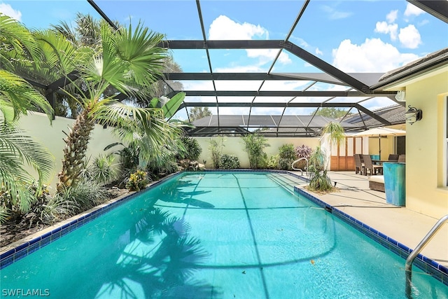 view of pool with glass enclosure and a patio area