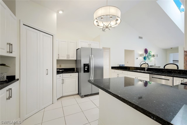 kitchen featuring a skylight, stainless steel appliances, white cabinetry, and light tile floors