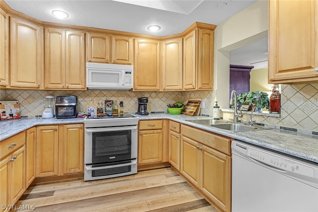 kitchen featuring light stone counters, sink, white appliances, tasteful backsplash, and light hardwood / wood-style flooring