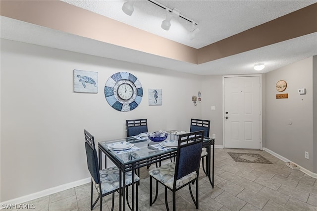 dining room featuring track lighting, light tile floors, and a textured ceiling