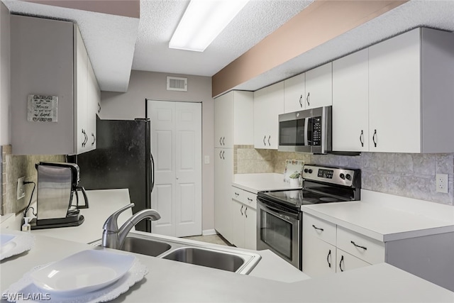 kitchen with backsplash, stainless steel appliances, a textured ceiling, white cabinets, and sink