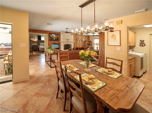 tiled dining room with a notable chandelier, washing machine and dryer, and a fireplace