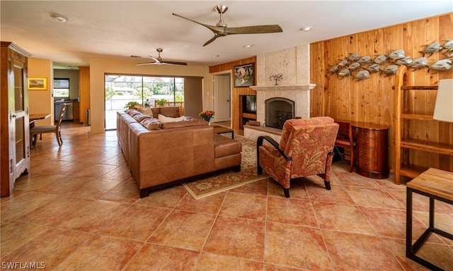 tiled living room with ceiling fan and a large fireplace