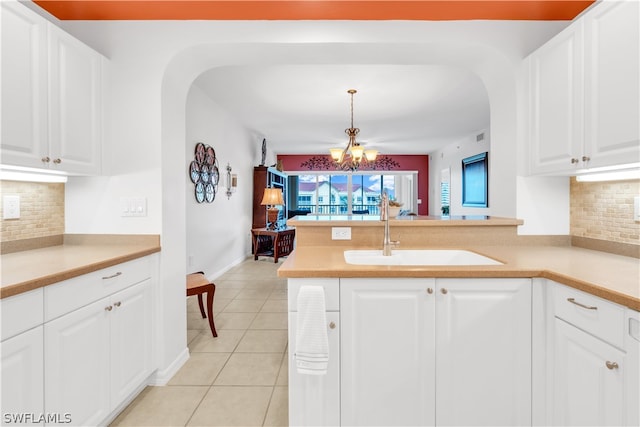 kitchen featuring tasteful backsplash, decorative light fixtures, white cabinetry, and light tile floors