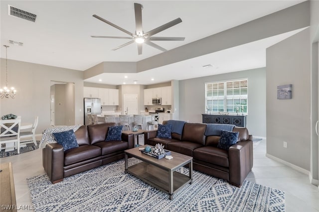 living room featuring light tile patterned floors and ceiling fan with notable chandelier