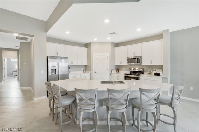 kitchen featuring white cabinets, appliances with stainless steel finishes, sink, and a large island with sink