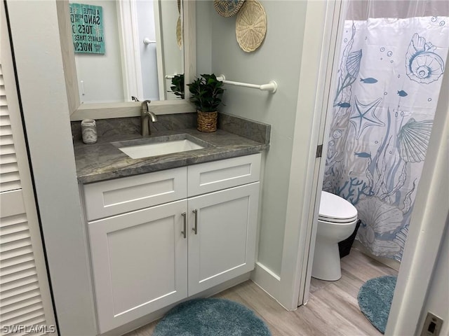 bathroom featuring hardwood / wood-style floors, toilet, vanity, and walk in shower