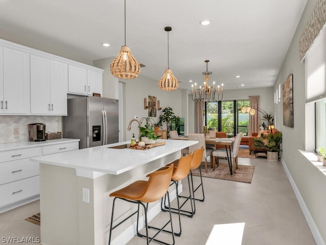 kitchen featuring stainless steel fridge with ice dispenser, a kitchen island with sink, light tile floors, and sink