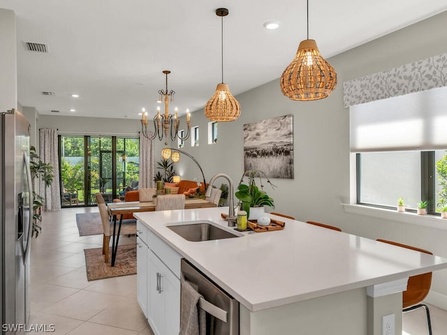 kitchen with stainless steel appliances, a center island with sink, sink, pendant lighting, and light tile floors