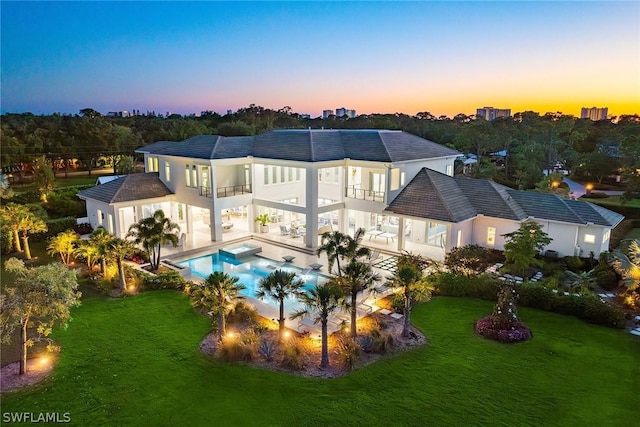 rear view of property featuring an outdoor pool, a patio area, a yard, and a balcony