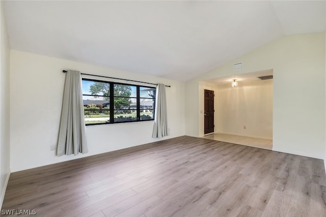 empty room with light hardwood / wood-style floors and vaulted ceiling