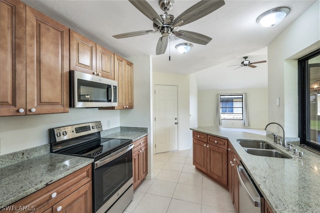 kitchen with light stone counters, sink, light tile patterned flooring, and appliances with stainless steel finishes