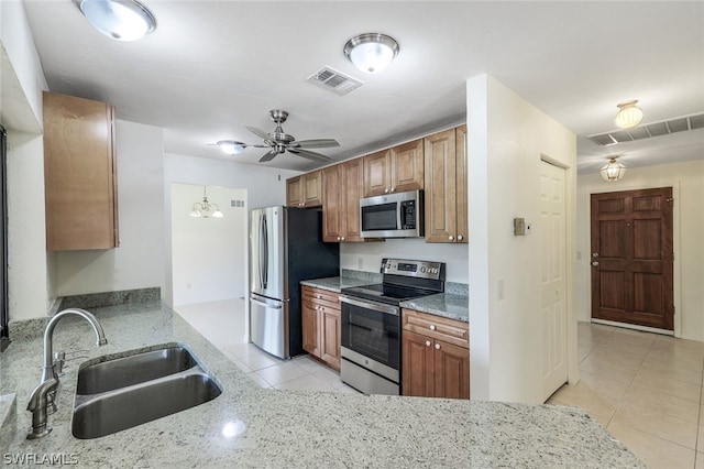 kitchen with sink, light tile patterned floors, ceiling fan, stainless steel appliances, and light stone countertops