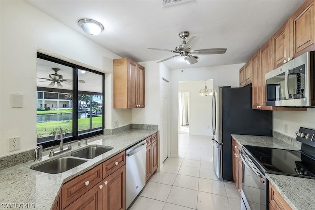 kitchen featuring sink, appliances with stainless steel finishes, light stone countertops, light tile patterned flooring, and ceiling fan with notable chandelier