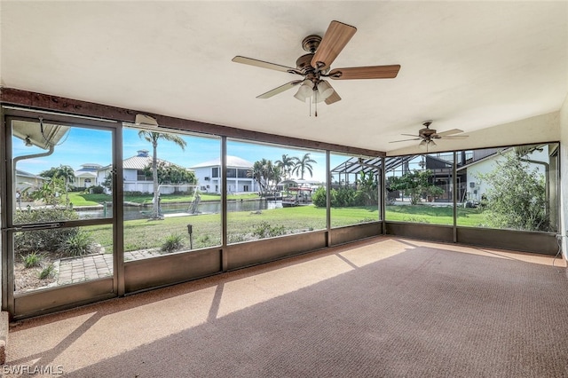 unfurnished sunroom with ceiling fan and a water view