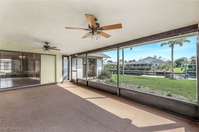 unfurnished sunroom with ceiling fan and a water view