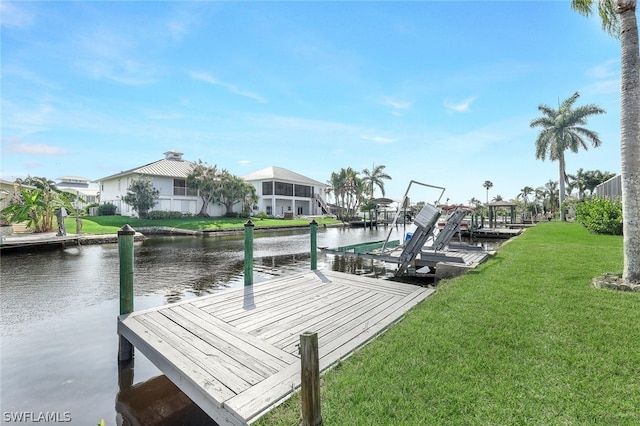 view of dock with a lawn and a water view