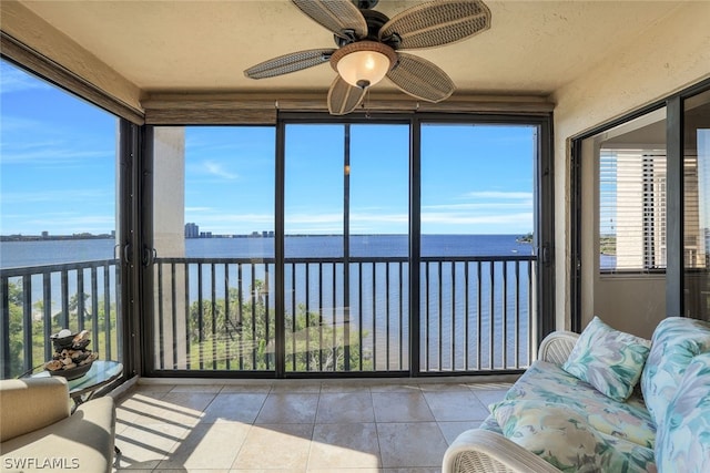 sunroom with ceiling fan, a water view, and a wealth of natural light